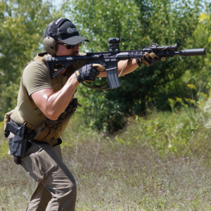 Participant aiming a carbine at an outdoor range