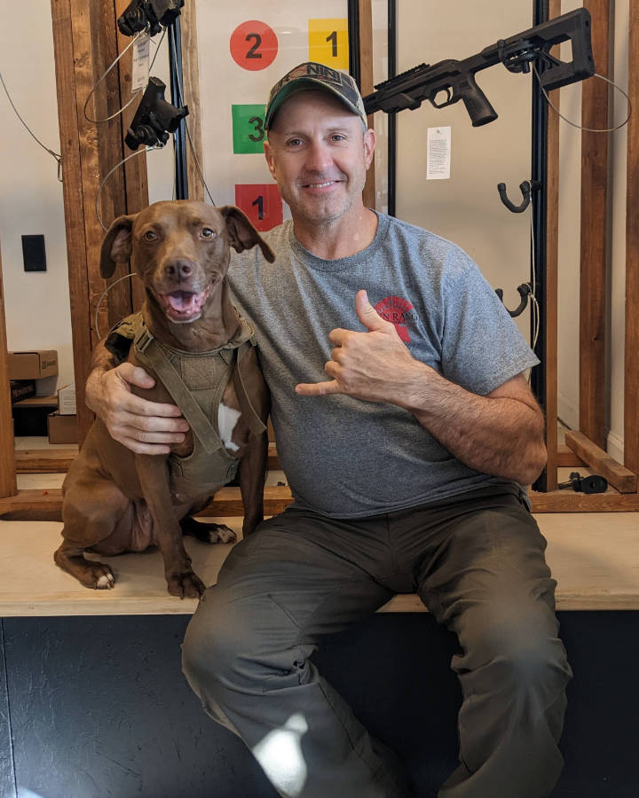 Brad Ferrari seated with a dog at Down Range