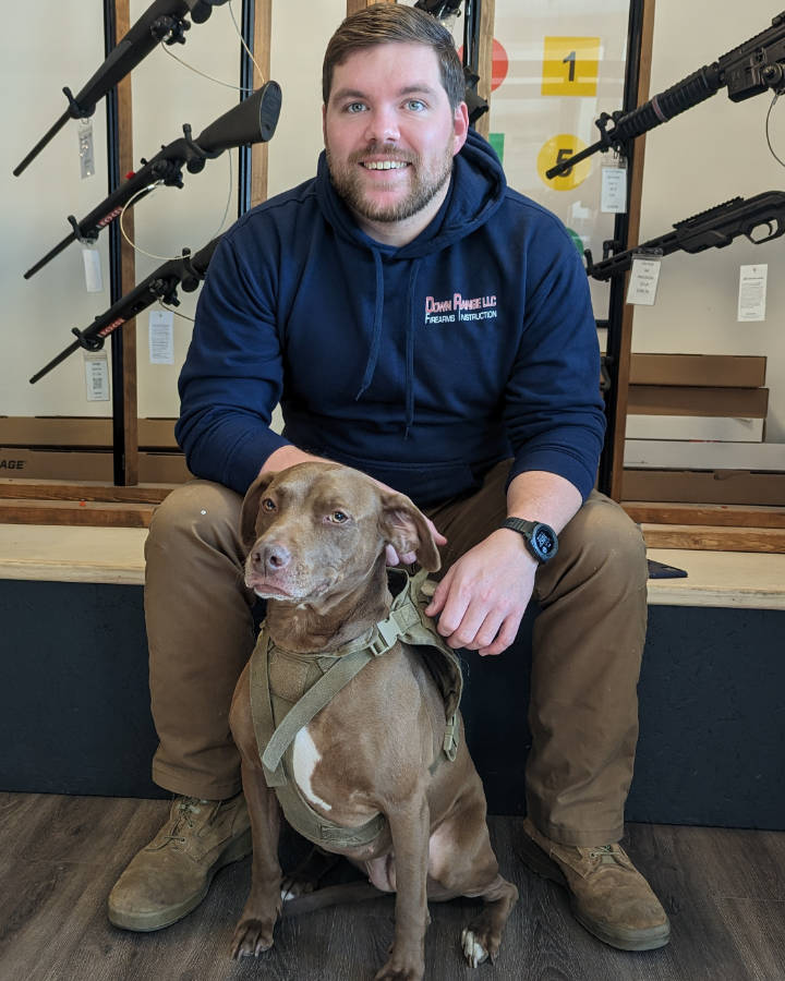 Cory Shepherd seated with a dog at Down Range