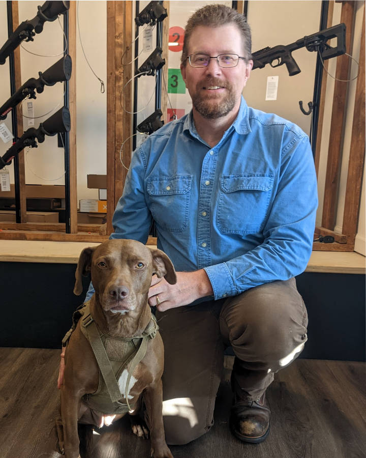 Mark Ackland seated with a dog at Down Range