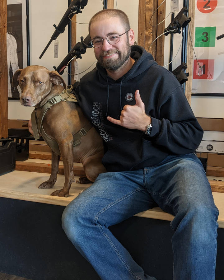 Matt Gerard seated with a dog at Down Range